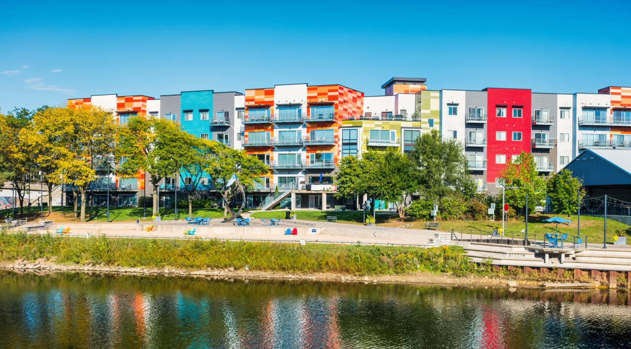 colorful building sitting on the backside or a river with a playground in between the building and the river